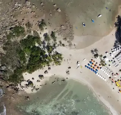 Vista aérea da Segunda Praia, com areia, coqueiros e guarda-sóis