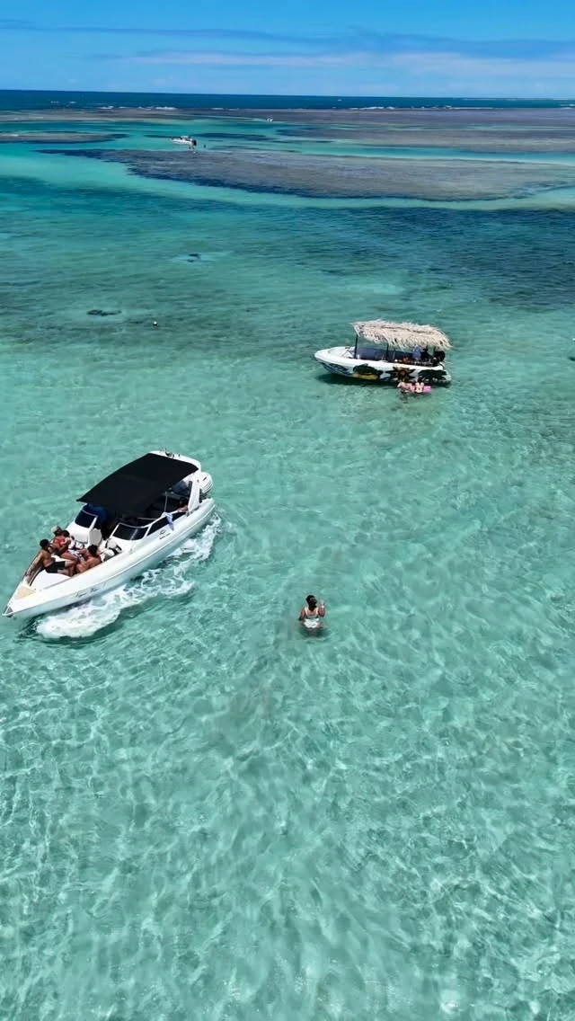 Lanchas em águas claras em imagem do passeio Volta à Ilha publicada pela Oceano Turismo. Consulte roteiro e condições com a agência.